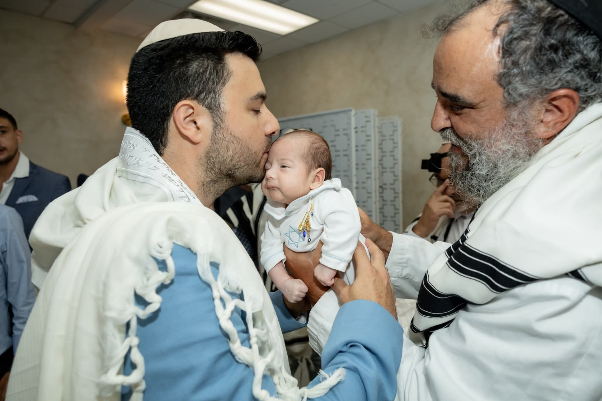 Rabbi Yossi Srugo hands a newborn baby to the sandek during a Brit Milah ceremony on Shabbat or Yom Tov
